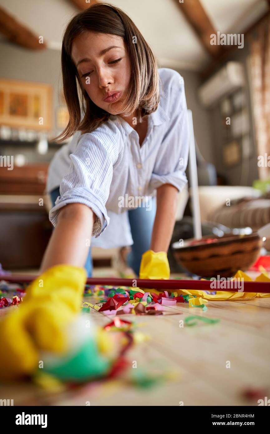 tired young woman cleaning the house after a birthday party - closeup Stock Photo