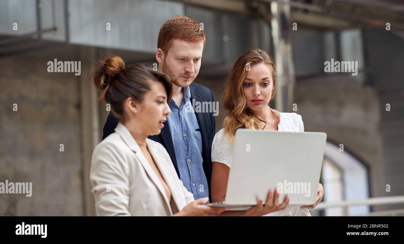 group of three , two women and one man, looking at content on laptop Stock Photo