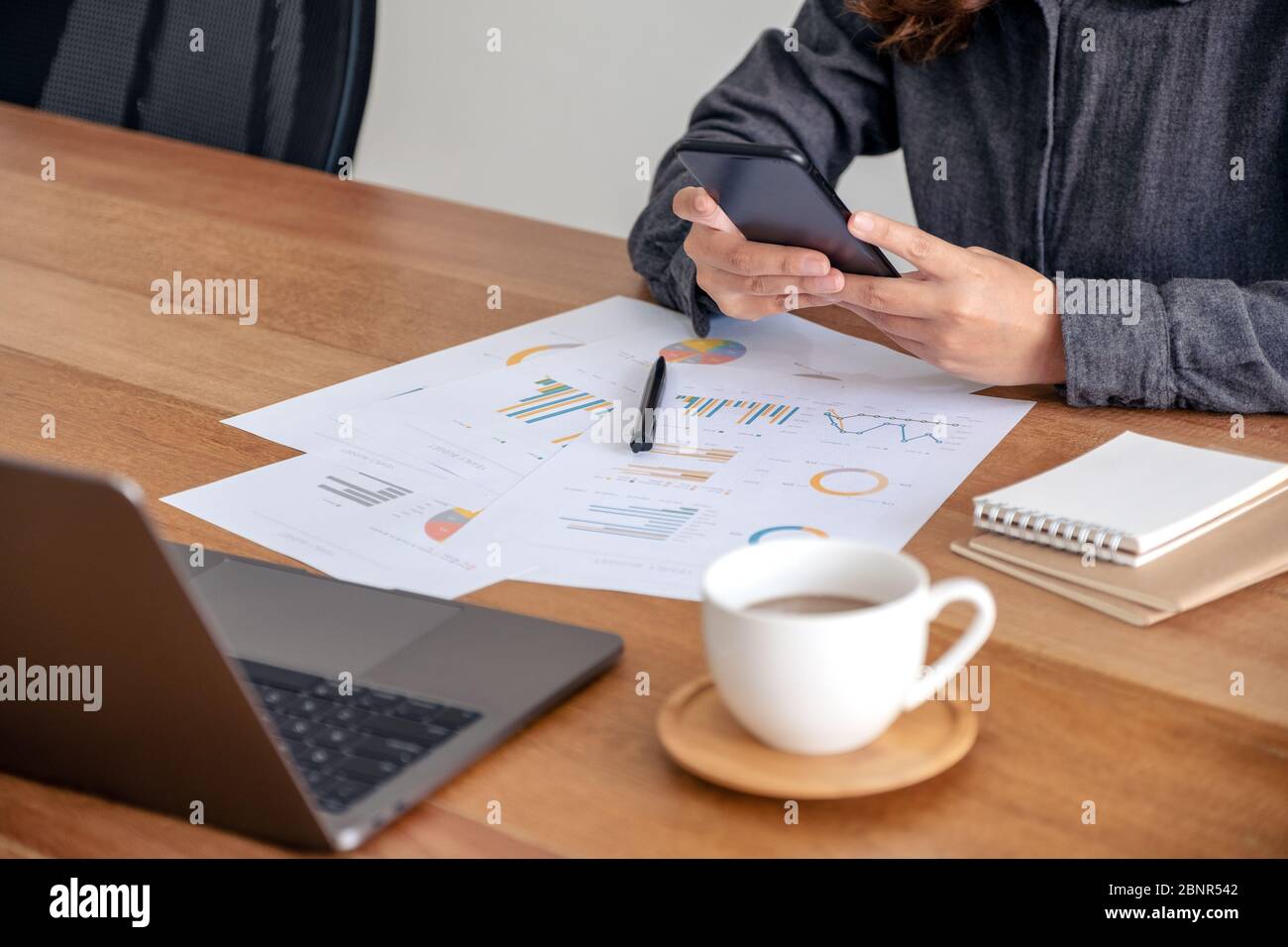 A businesswoman using mobile phone while working on business document ...