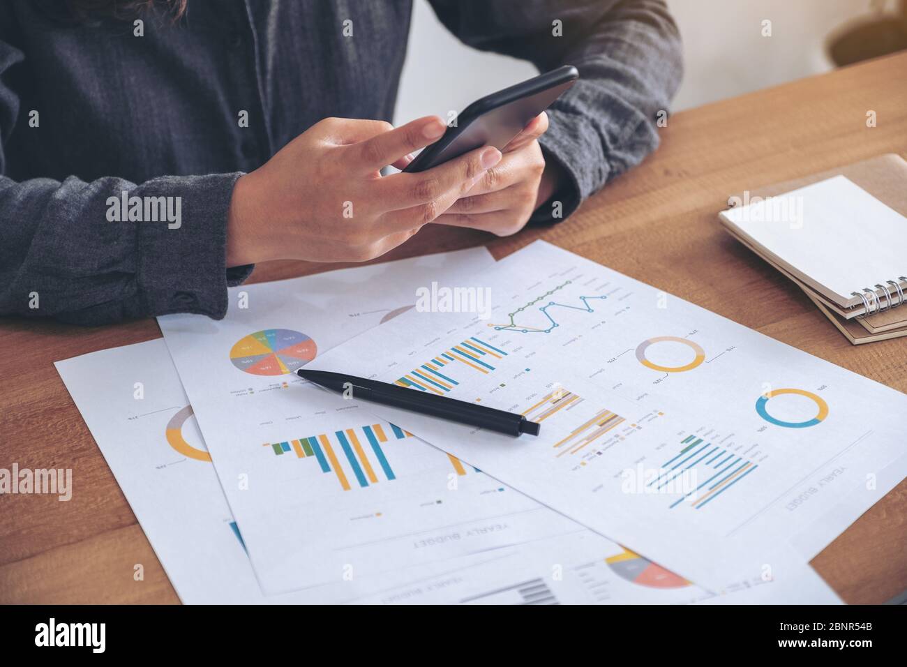 A businesswoman using mobile phone while working on business document ...