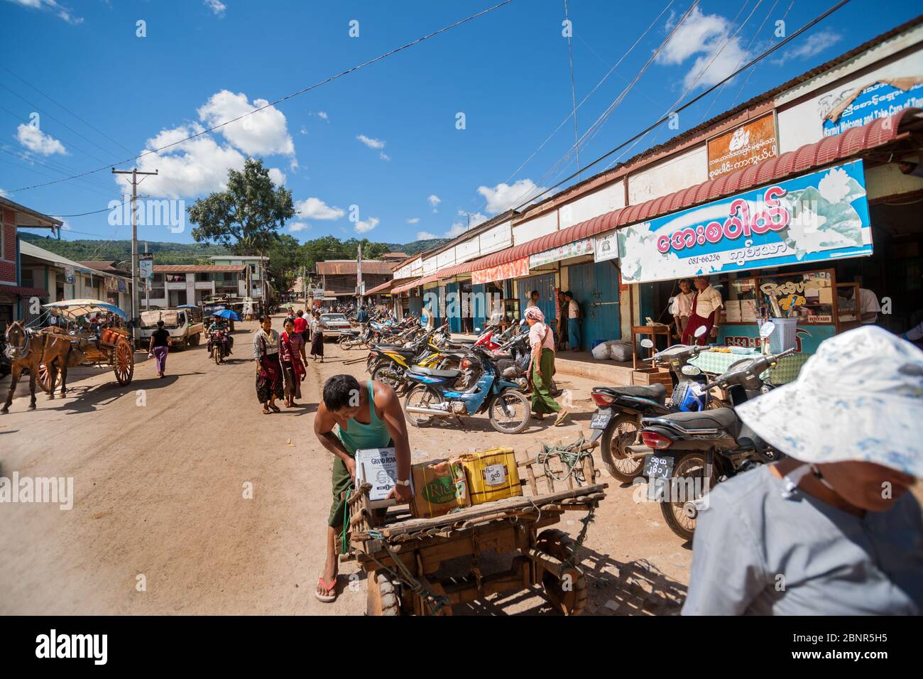 Pindaya Myanmar - November 1 2013; Main street in small rural town unpaved with people , motorcycles and horses ans carts lined on both sides by shops Stock Photo