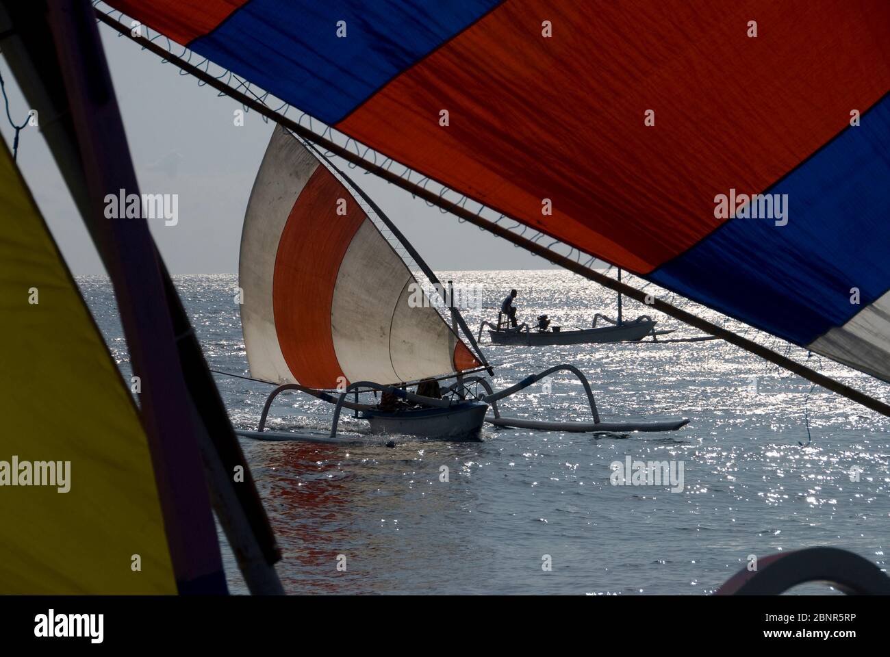 Outrigger canoe on water with colorful sails during Jukung Race, Tulamben, Bali, Indonesia Stock Photo