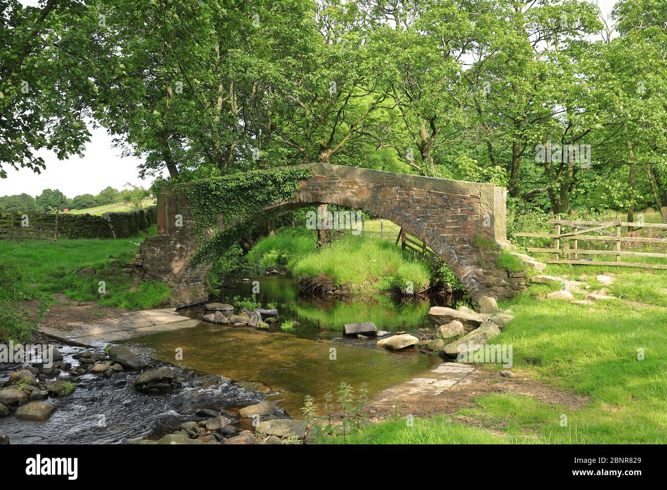 A stone bridge crosses a stream in the West Yorkshire countryside close to the village of Haworth in northern England. Stock Photo