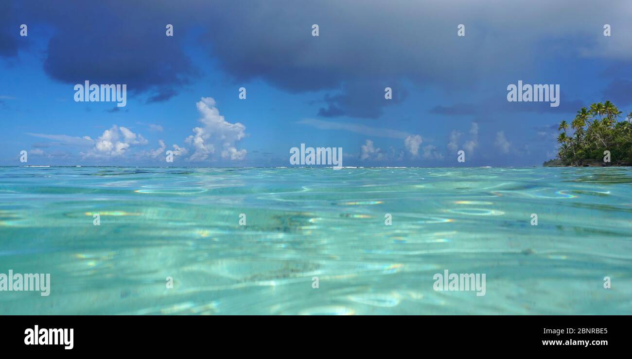 Tropical seascape, turquoise water of a lagoon with cloudy blue sky seen from water surface, French Polynesia, Pacific ocean, Oceania Stock Photo