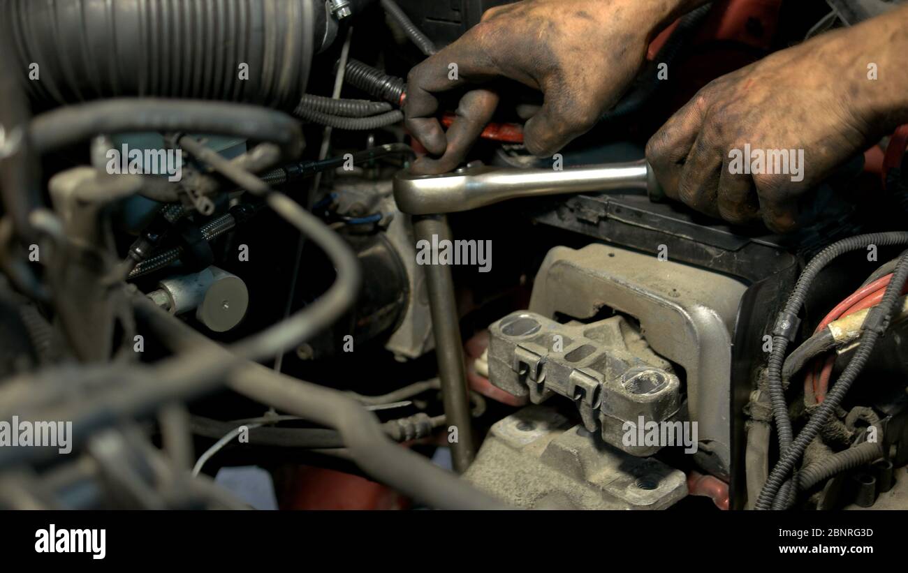 Close up mechanic hands screwing something in a car engine mechanism. Stock Photo