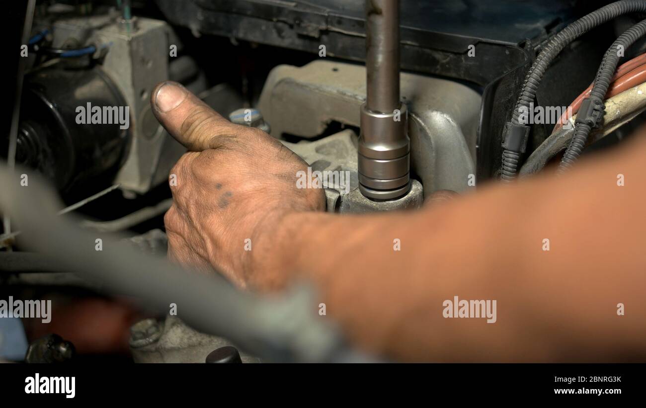 Auto mechanic working on car engine in mechanics garage. Stock Photo