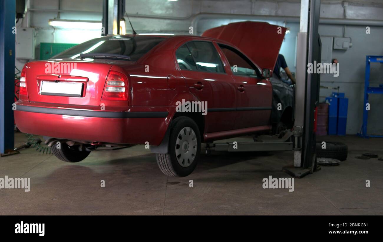 Mechanic is moving gas tank on trolley to do welding the bottom of the car. Stock Photo