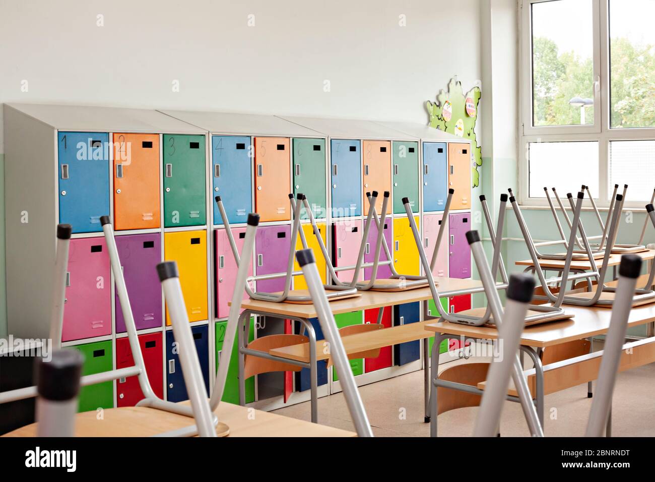 Close up of modern empty classroom with colorful lockers and raised chairs on the tables - back to school Stock Photo