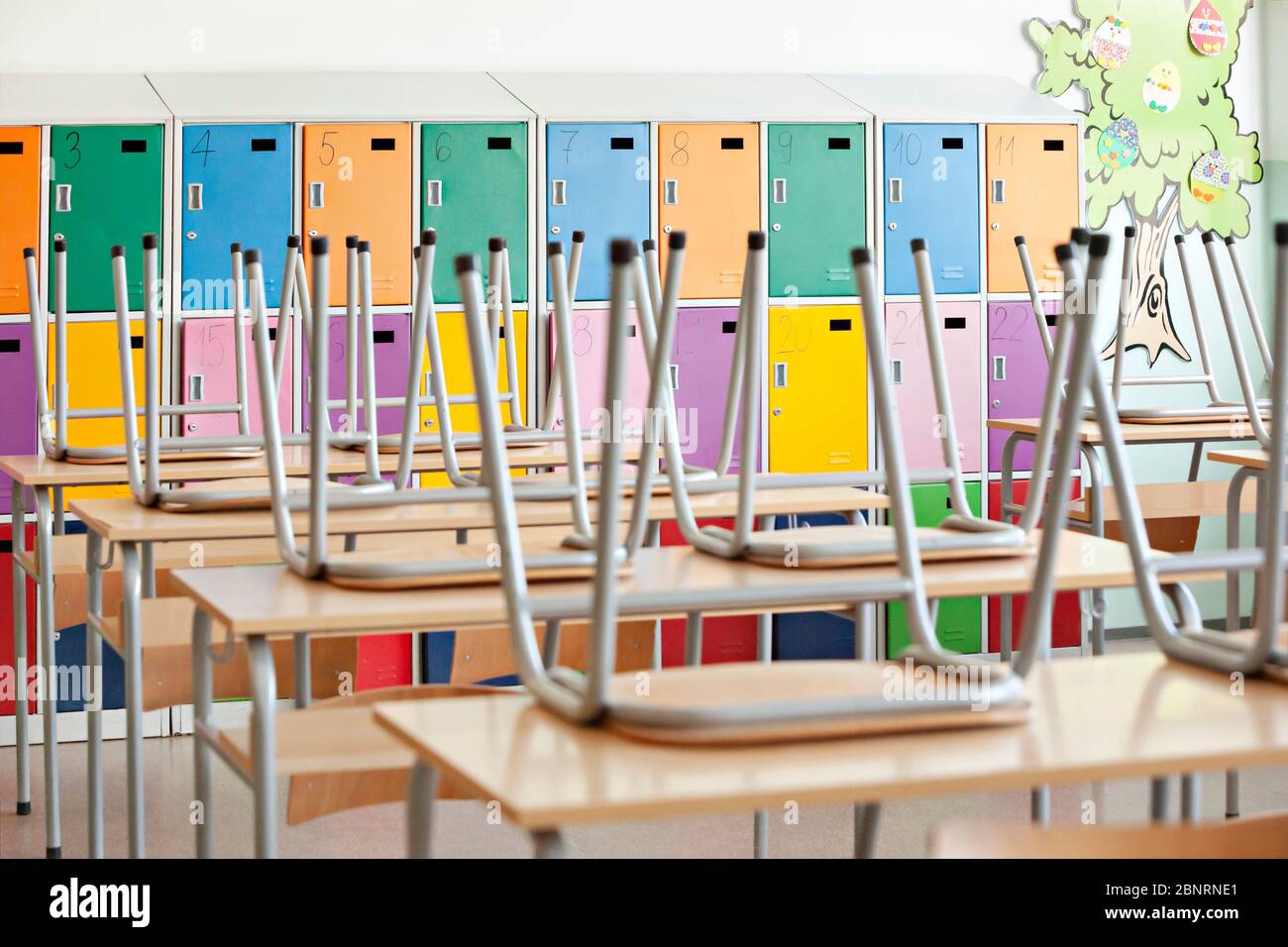 Modern empty classroom with colorful lockers and raised chairs on the tables - back to school Stock Photo