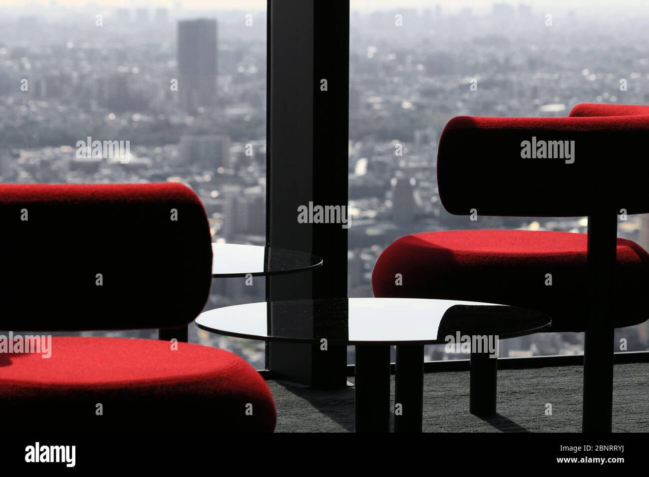 Modern cafe table lined up by the window of the lounge of a skyscraper with a view of the city Stock Photo