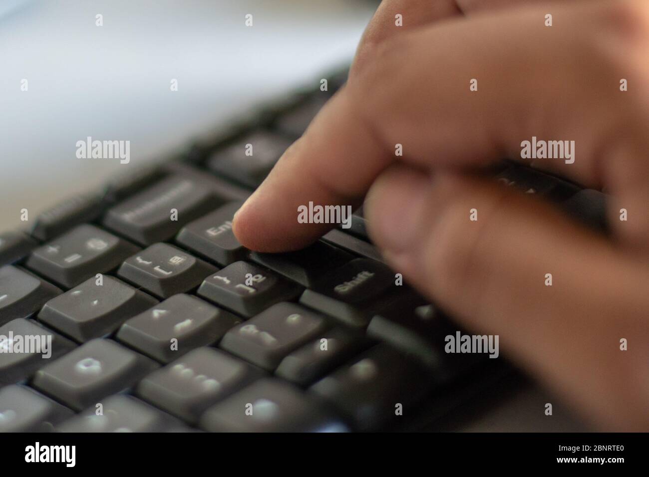 Finger on the enter key - hand pressing "enter" button on computer Stock Photo