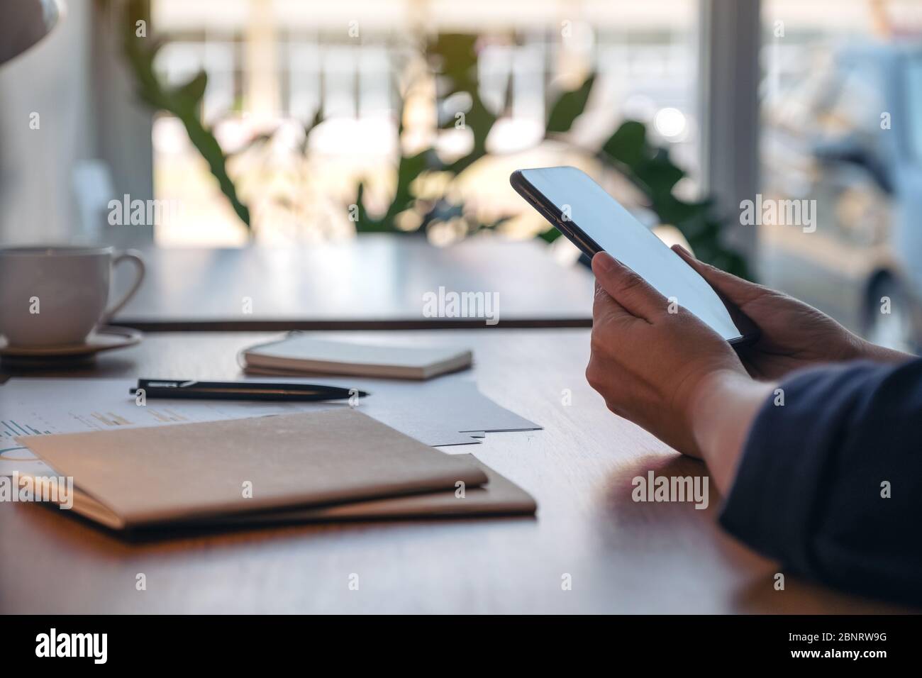 Closeup image of a woman holding and using mobile phone while working ...