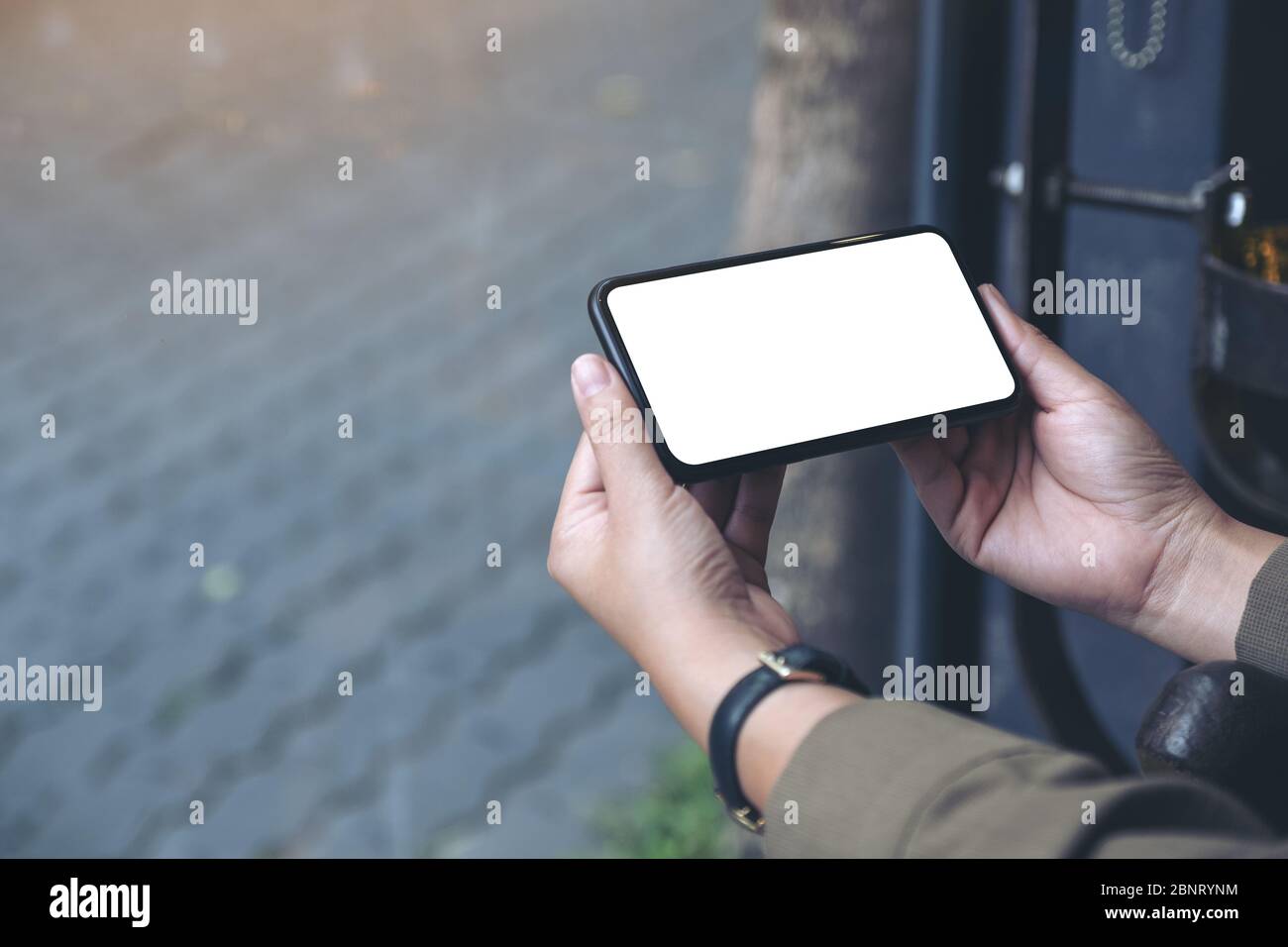Mockup image of hands holding black mobile phone with blank desktop