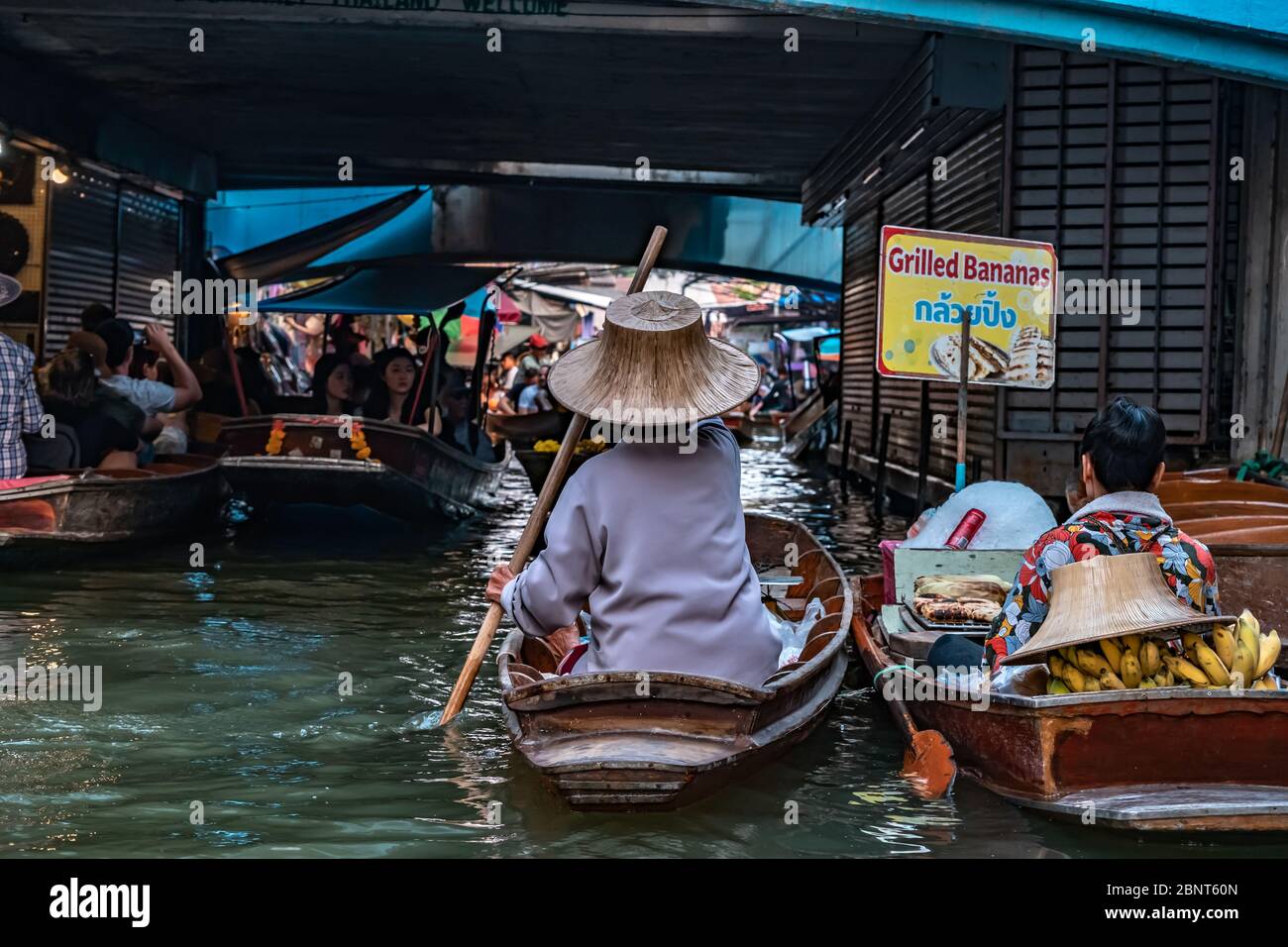 Ratchaburi, Damnoen Saduak / Thailand - February 11, 2020: Name of this place Damnoen Saduak Floating Market. Vendor woman scull the boat with her hat Stock Photo