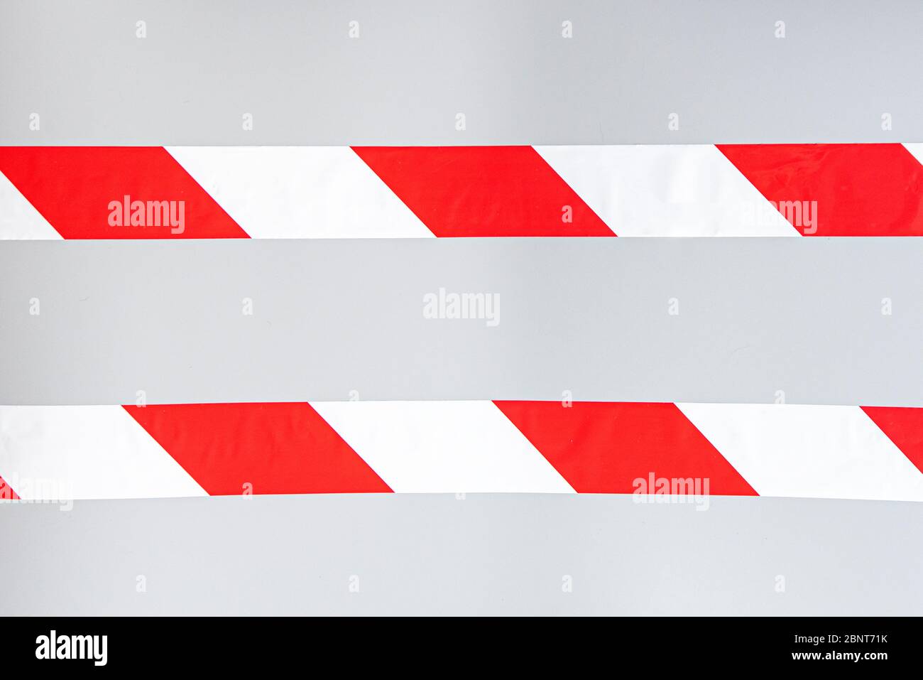 Red white signal striped interdictory tape. Striped line isolated on gray background. Plastic warning tape. Stock Photo