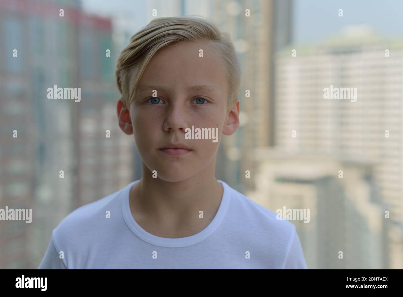 Face of young handsome boy with blond hair against view of the city ...