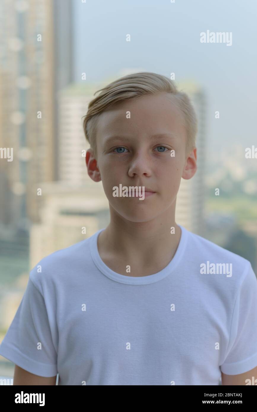 Face of young handsome boy with blond hair against view of the city ...