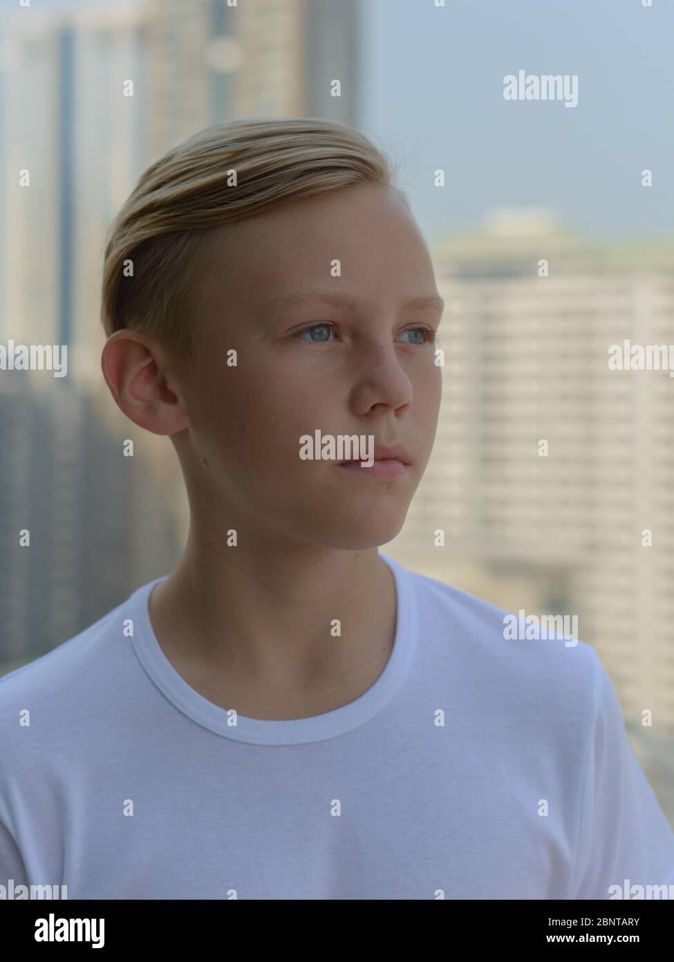 Face of young handsome boy with blond hair thinking against view of the ...
