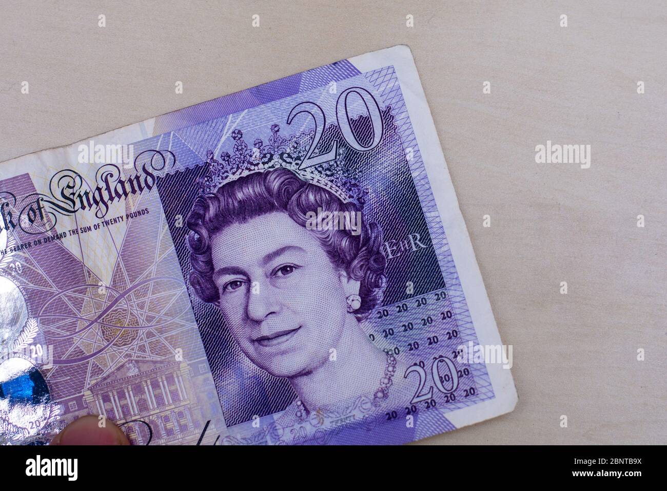 Persons hand giving the Currency of the England in the United Kingdom - One purple twenty pound note spread out on a white background. Money exchange. Stock Photo