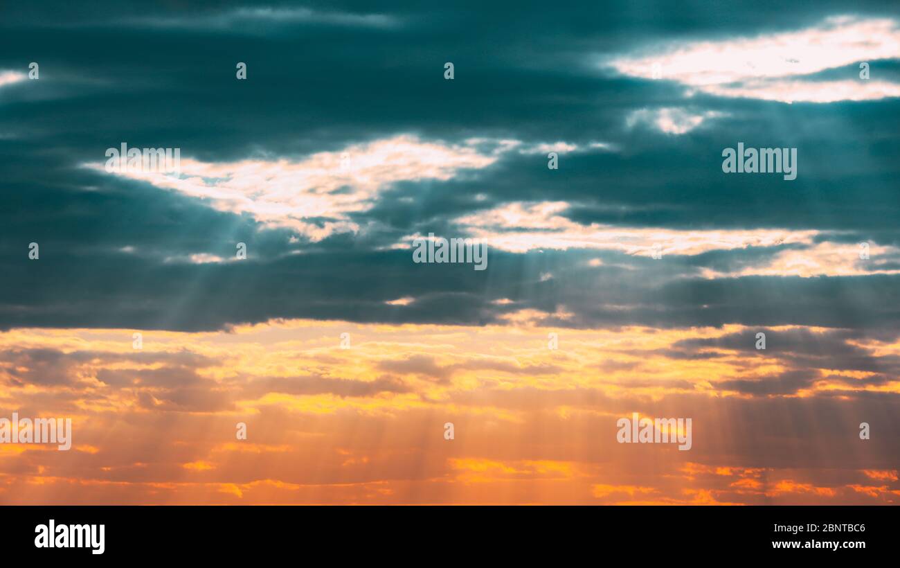 Sun Rays Shining Through Cloudy Sky With Fluffy Clouds. Sunset Sky During Rain. Stock Photo
