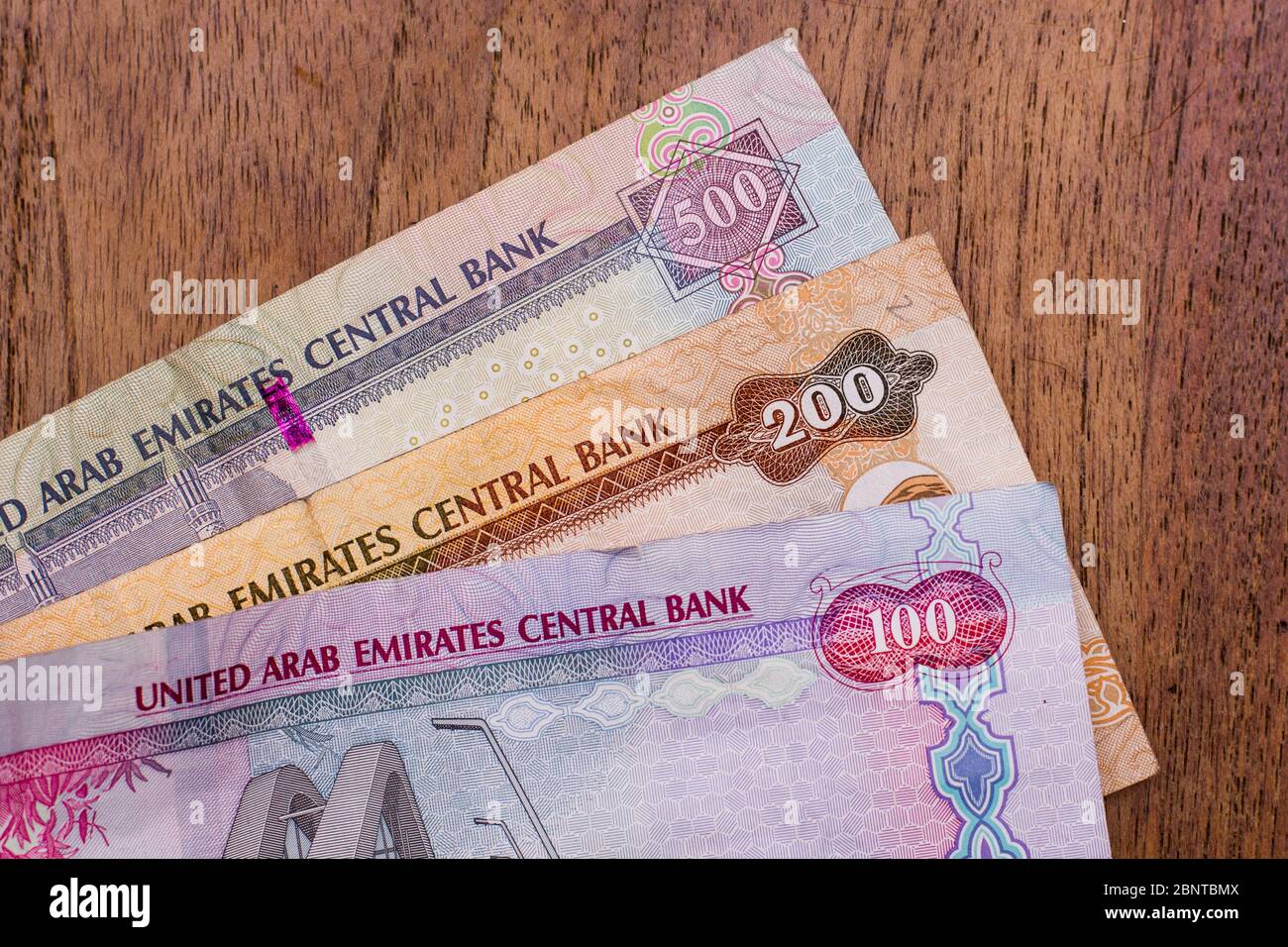 The Currency of the United Arab Emirates (UAE) - Close up of hundred Dirham notes on a brown table background. Money exchange. Stock Photo
