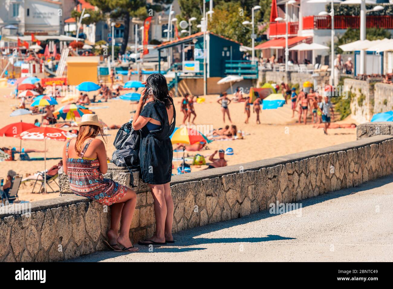 SaintPalaissurMer, France Two young women on the promenade look at the busy Plage du Bureau SaintPalaissurMer, France Two young women on the promenade look at the busy Plage du Bureau