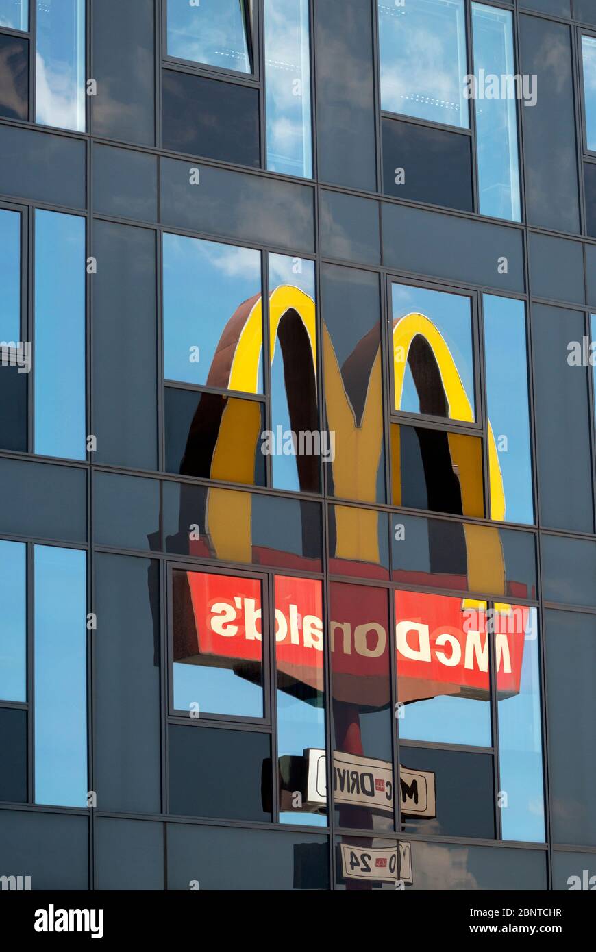Mirrored McDonald's logo and sign reflects off glass building as unusual uncommon unique view composition Stock Photo