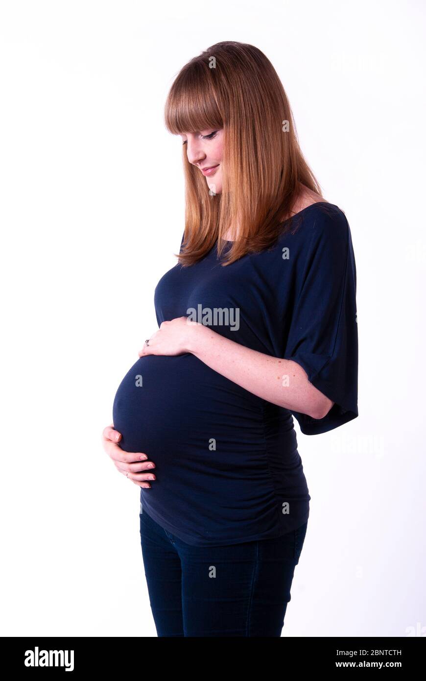 A studio portrait of a young pregnant woman holding her pregnant belly ...