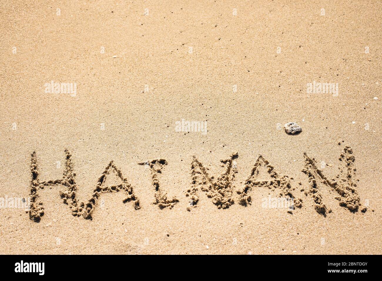 Word Hainan written in the sand seashore of tropical beach in Hainan Island China with authentic coral stone. Copy space for text Stock Photo