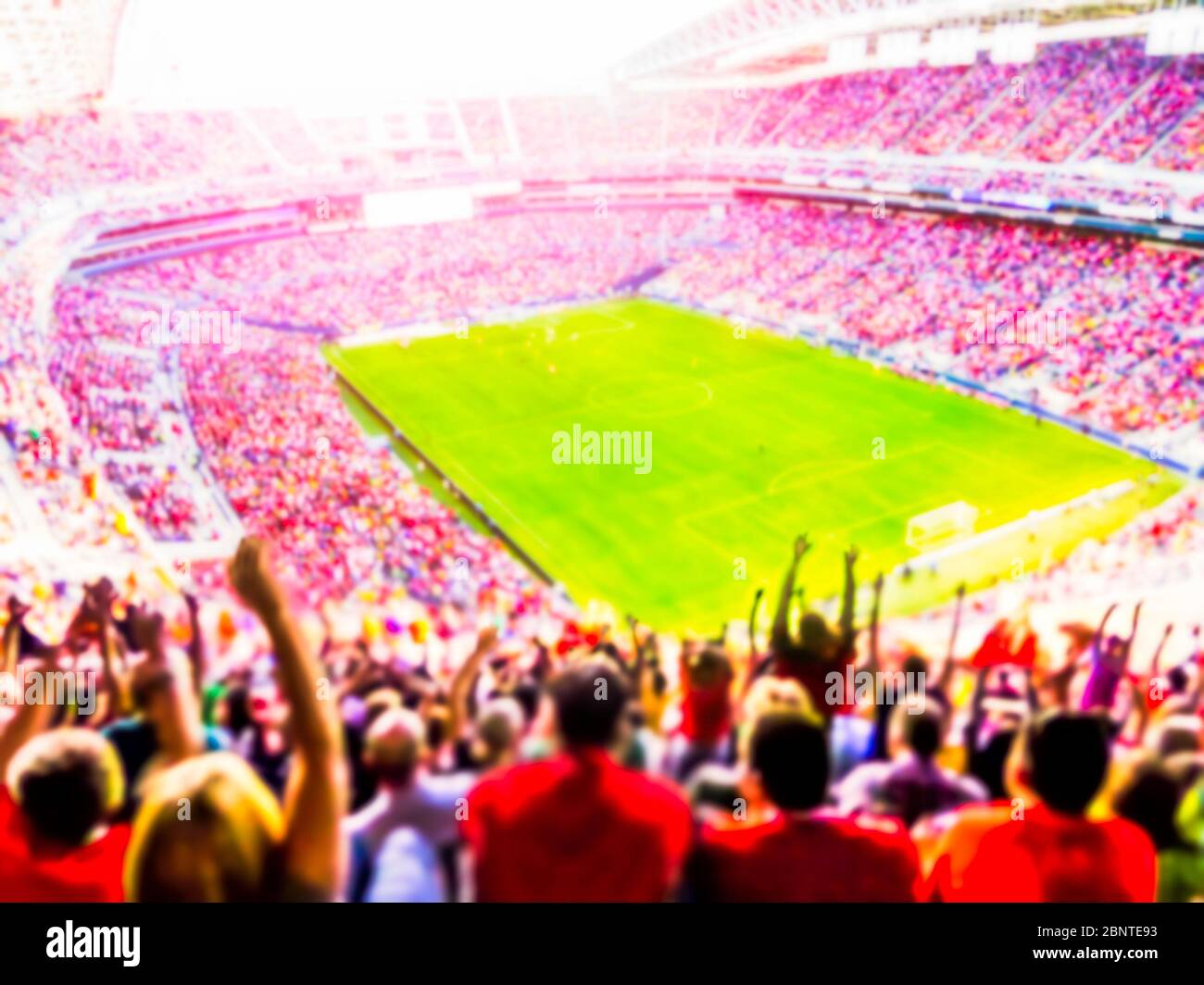 Football- soccer fans cheer their team and celebrate goal in full stadium with open air  with bright lighting beam     -blurred. Stock Photo