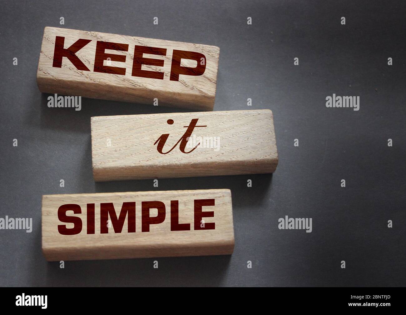 Keep it simple words on wooden blocks on dark gray background. Business