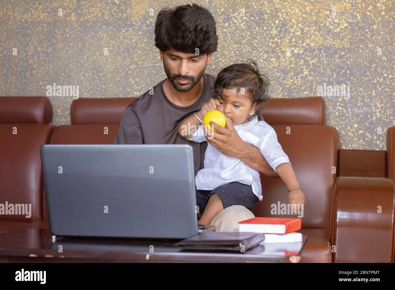 Young father with his little son working on laptop at home - Concept of work form home or wfh reality, People Lifestyles and technology Stock Photo