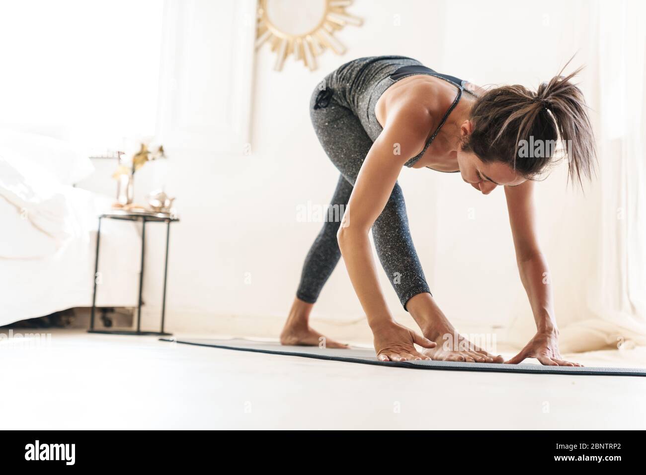 Photo of a young beautiful amazing strong fitness woman indoors at home make yoga exercises. Stock Photo