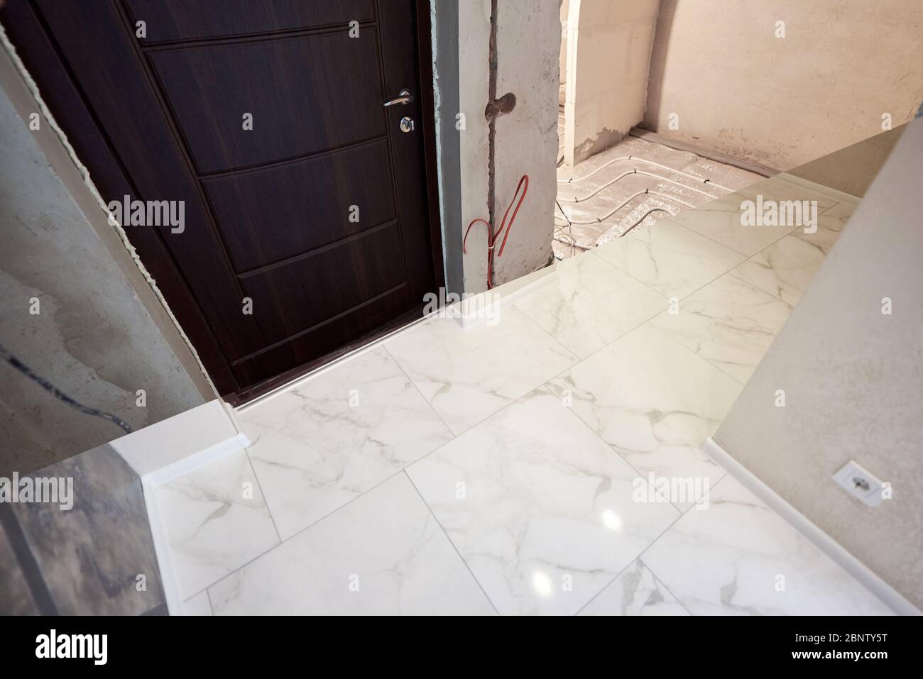 Comparison of old apartment with underfloor heating pipes and new flat with white marble floor and brown entrance door. Modern apartment before and after refurbishment. Concept of home restoration. Stock Photo