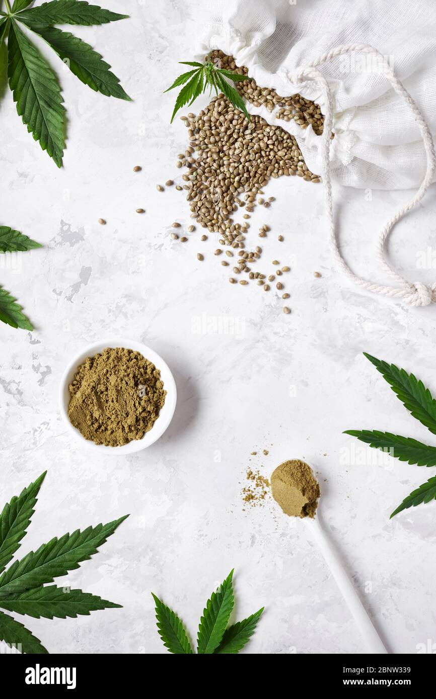 Hemp seeds and hemp protein powder on white background around cannabis leaves flat lay. Best for began diet Stock Photo