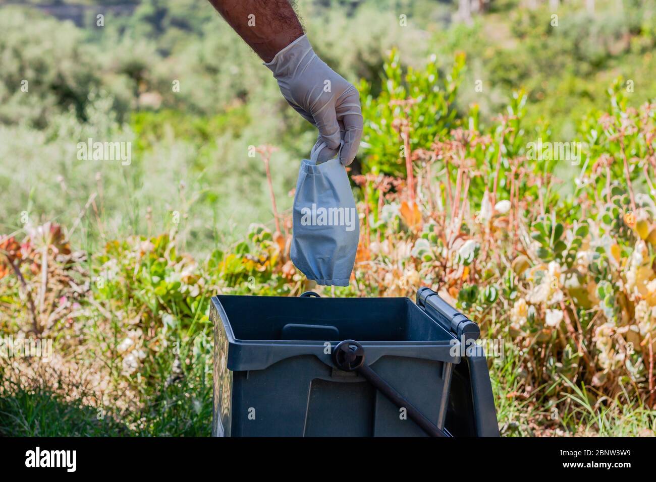 Man throwing used surgical mask into recycling bin. Waste disposal problem in coronavirus times, covid-19 Stock Photo