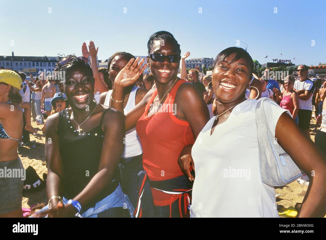 Smiling, happy & waving at the camera Afro-Caribbean teenage girls at a beach concert, Great Yarmouth, Norfolk, England, UK Stock Photo