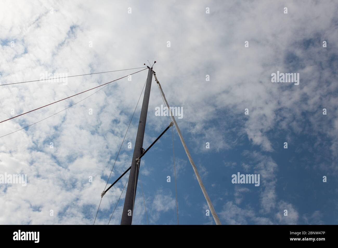 Sailing ship mast and rigging against a blue sky with clouds ...