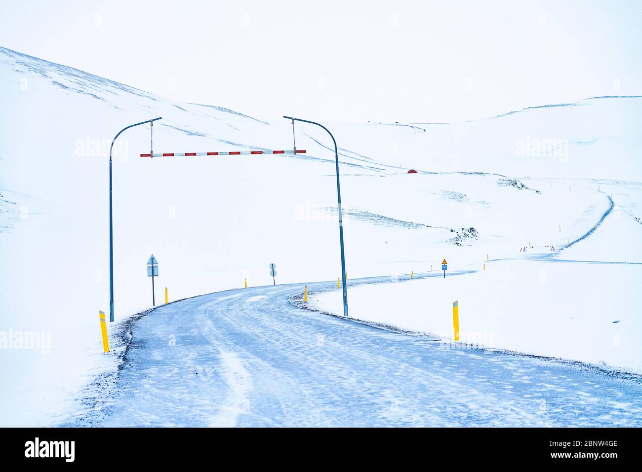 Snow covered Icelandic road snaking up to a mountain pass trough a snow covered landscape Stock Photo
