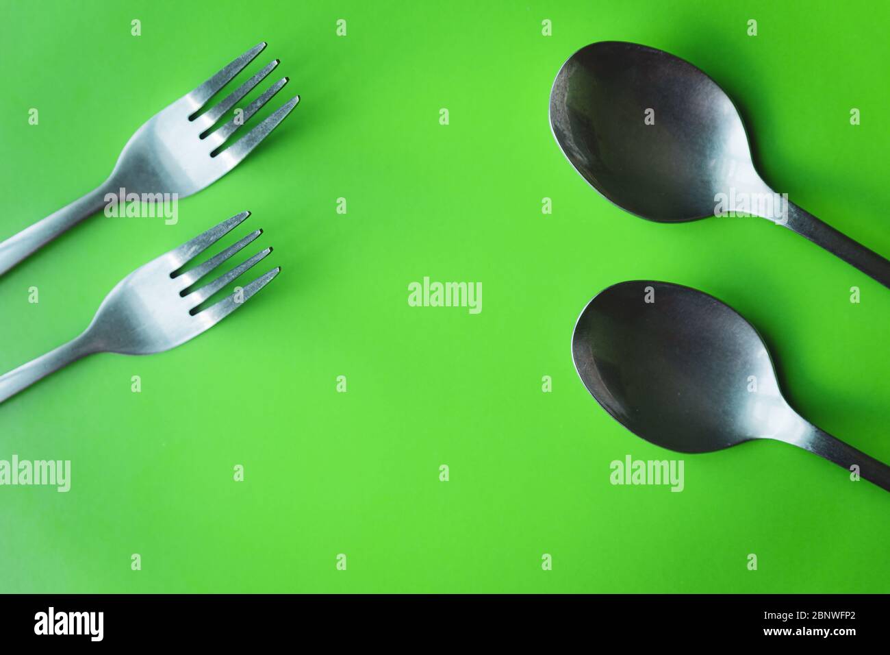 Metal forks and spoons cutlery on green background flat lay Stock Photo