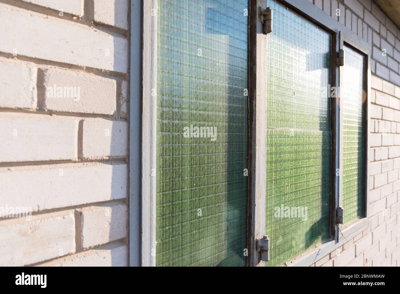 Green window with bars in a white brick building Stock Photo - Alamy