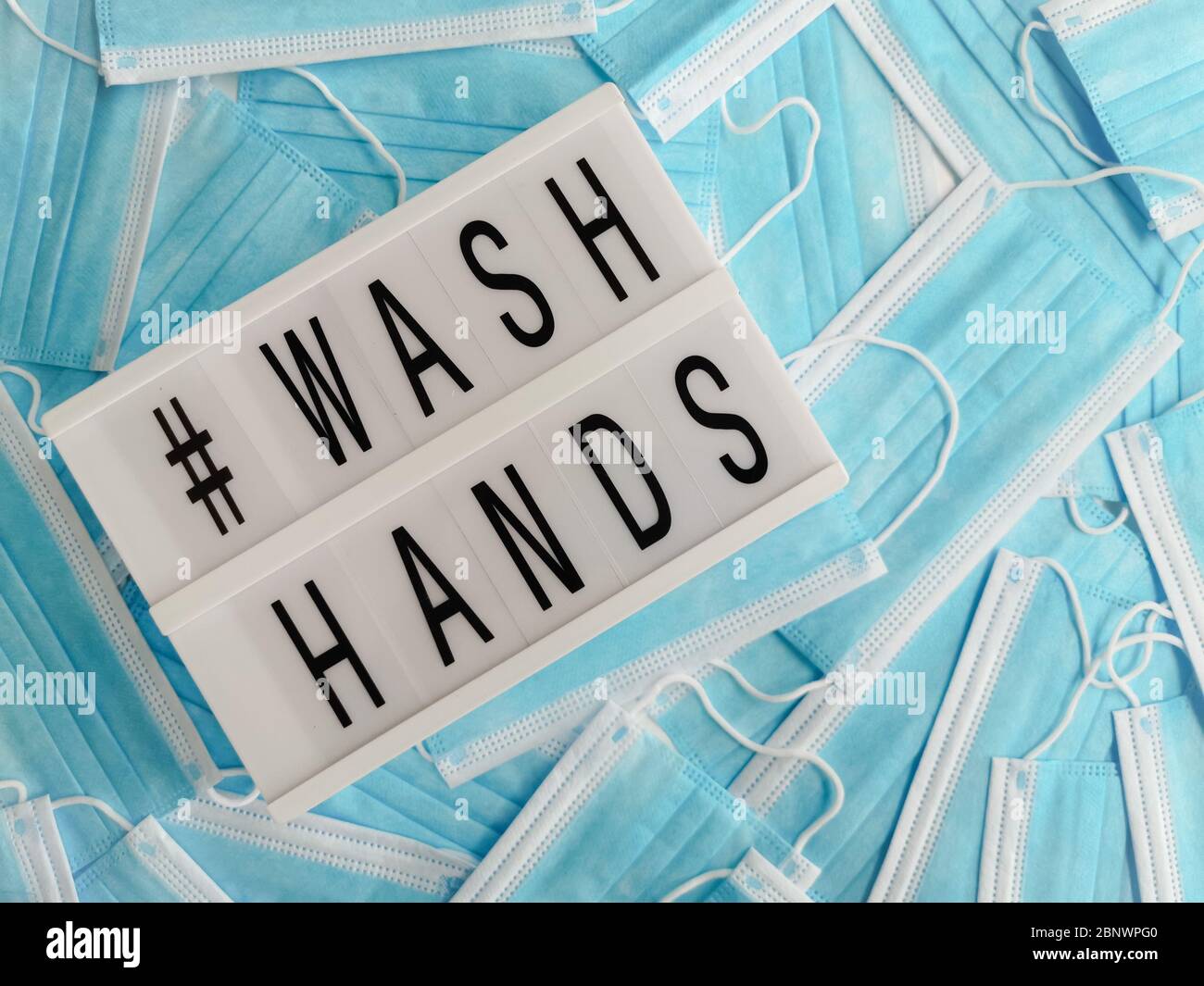 Blue surgical face masks with a white light box stating # Wash Hands Stock Photo