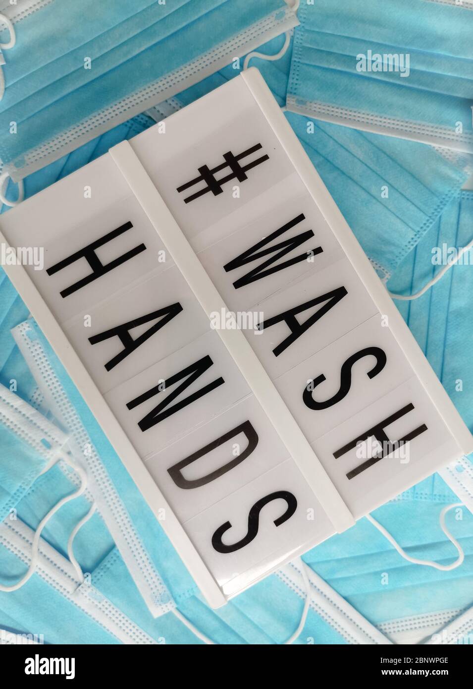 Blue surgical face masks with a white light box stating # Wash Hands Stock Photo