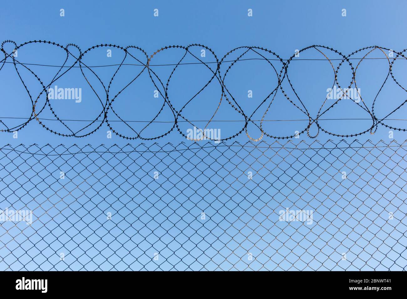 Barbed wires reinforced fence and sky. Stock Photo