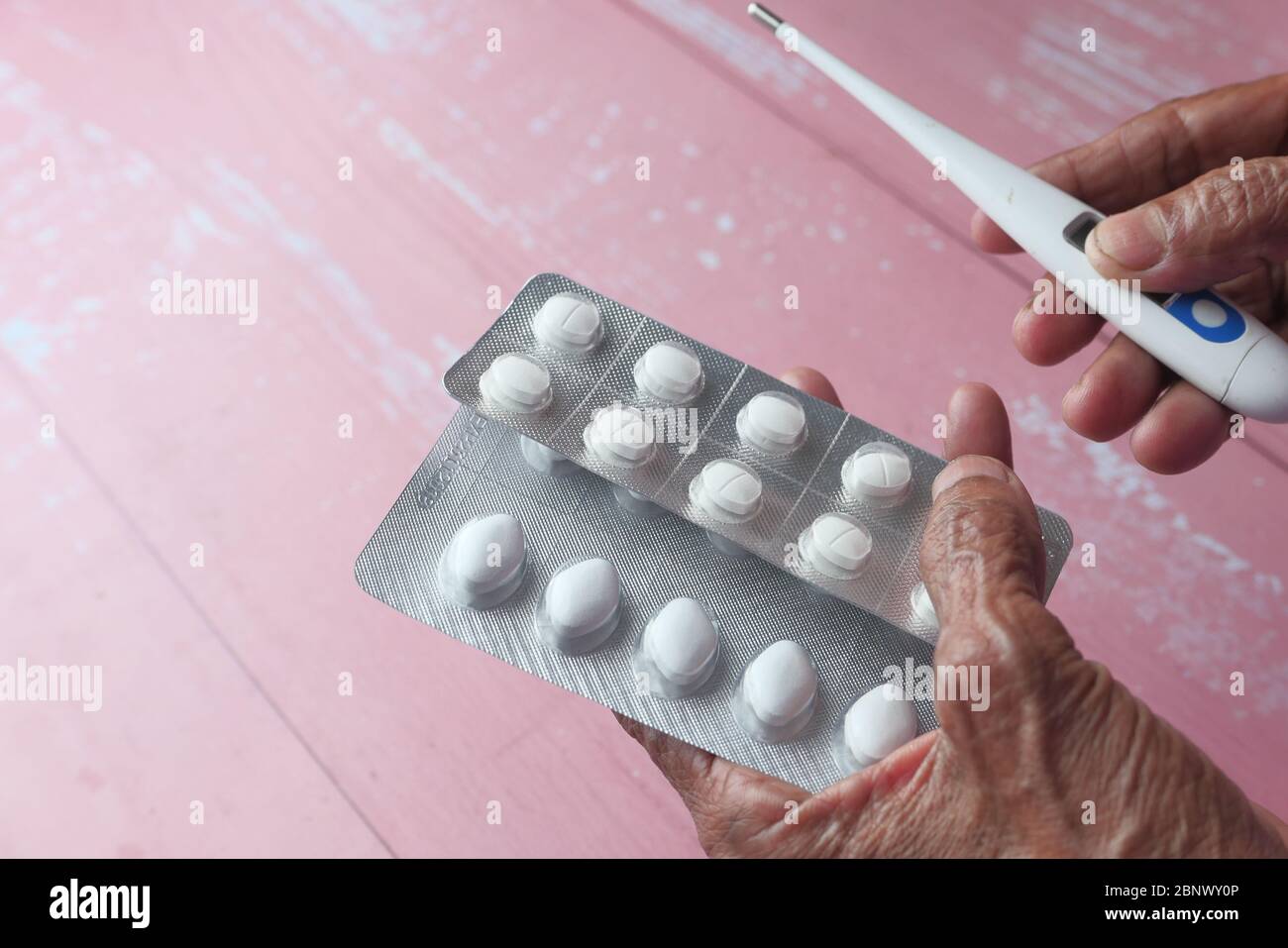 Elderly woman hand holding blister pack and thermometer Stock Photo Alamy