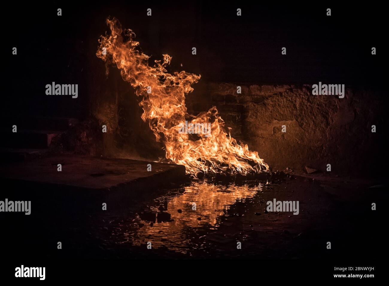 Huge fire burning off of lubricant oil and motor parts beside a garage