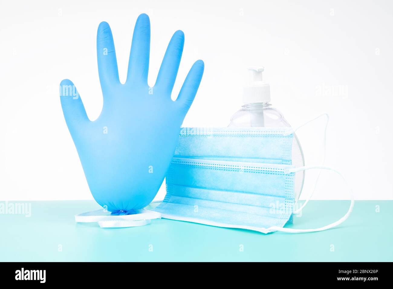 Inflated nitrile disposable glove with a protective medical mask and a plastic bottle of antibacterial hand sanitizer gel - a virus spread protection Stock Photo