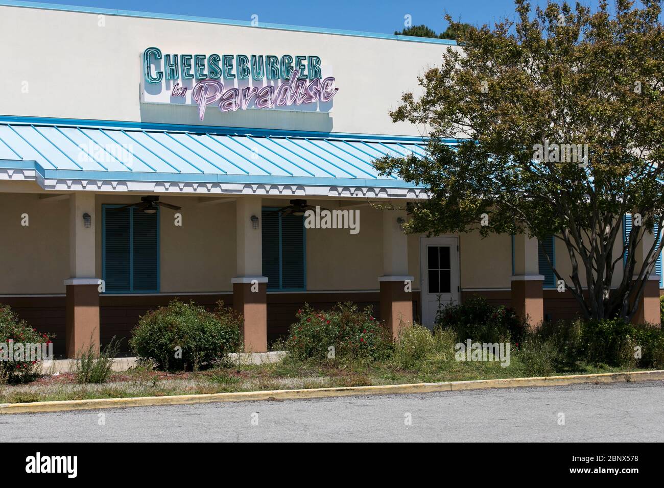 A logo sign outside of a closed and abandoned Cheeseburger in Paradise