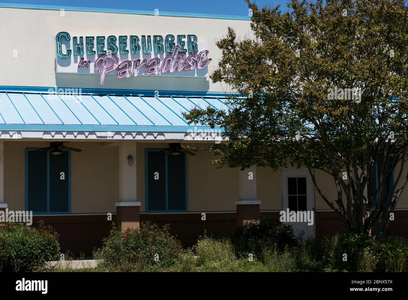 A logo sign outside of a closed and abandoned Cheeseburger in Paradise