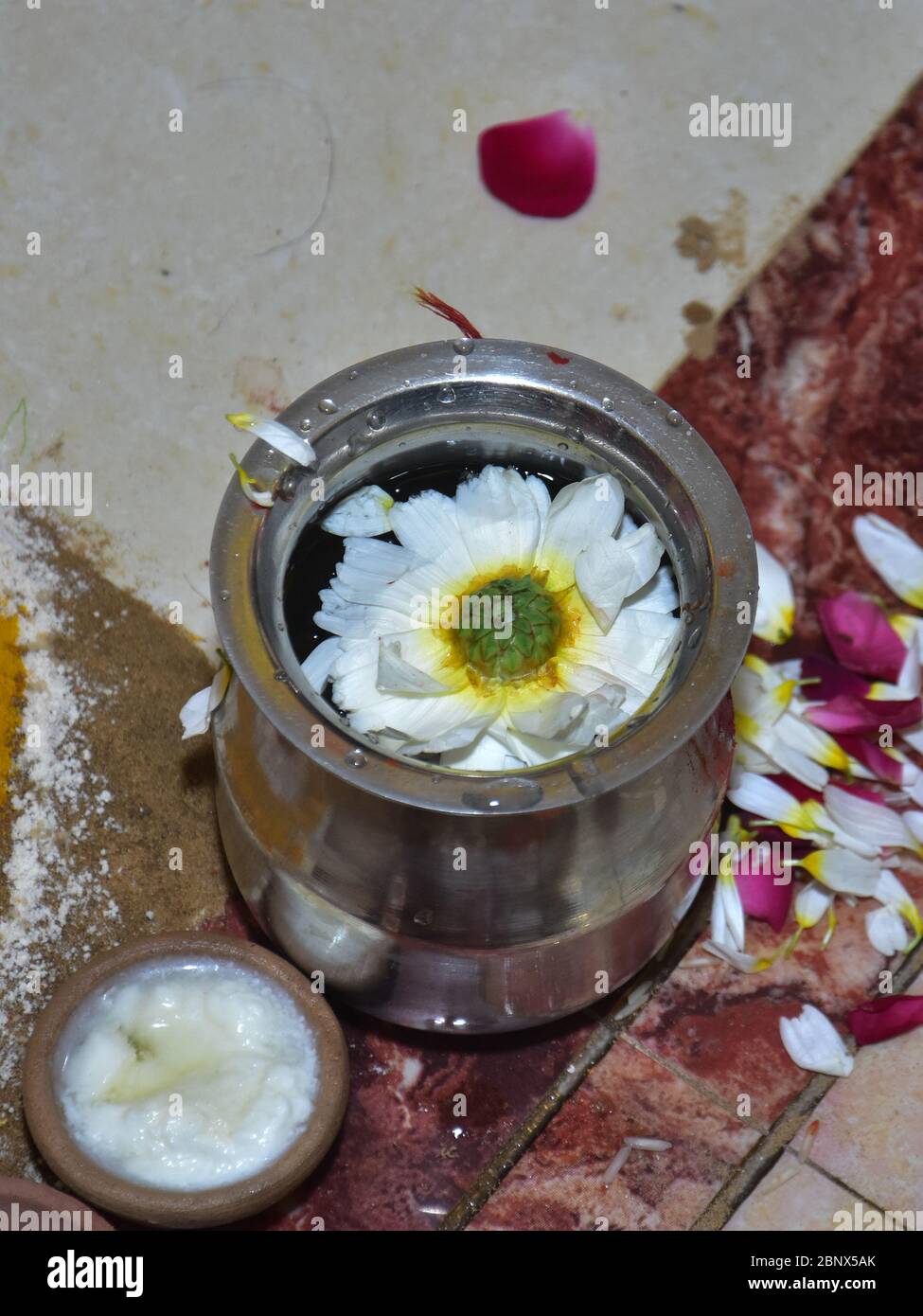 A view of a marigold flower floating in water in a steel pot Stock Photo